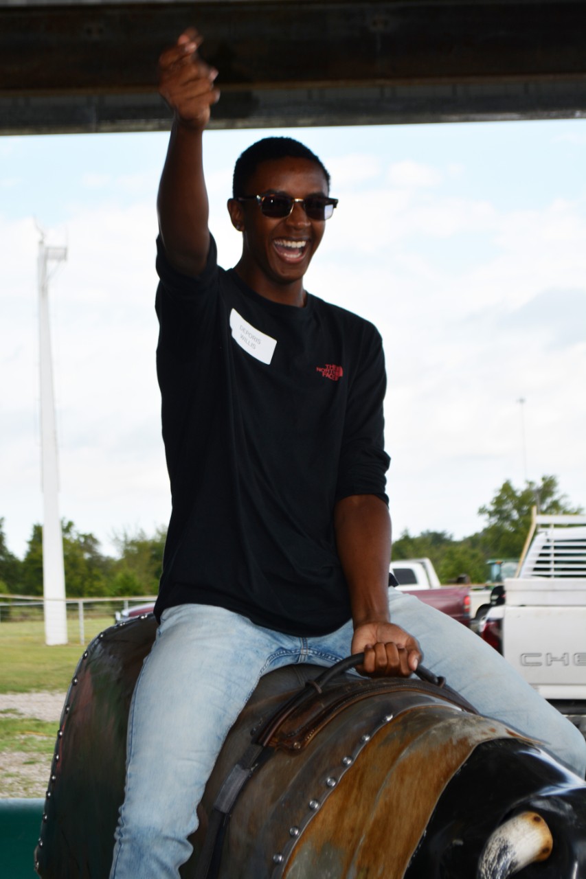 Young man rides mechanical bull.