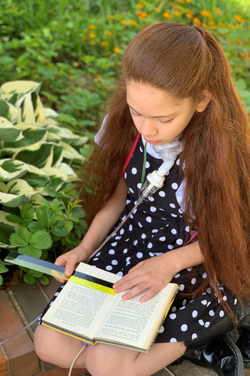 Girl highlights text in book with device