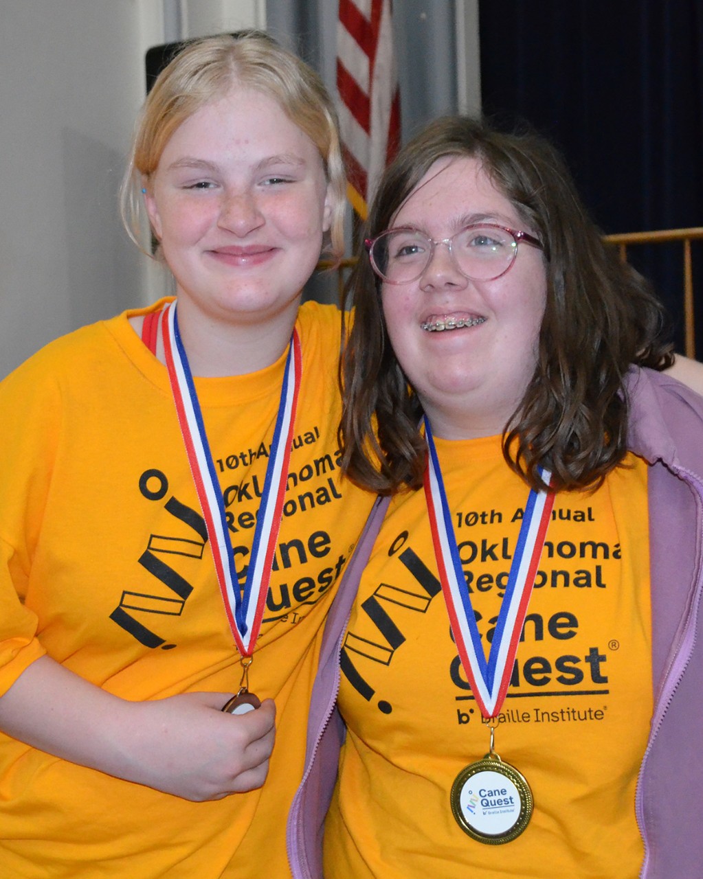 Two smiling young women wearing medals.