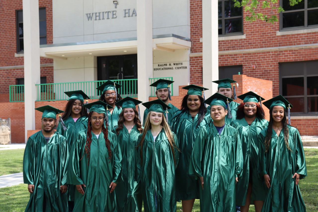 thirteen students wearing caps and gowns.