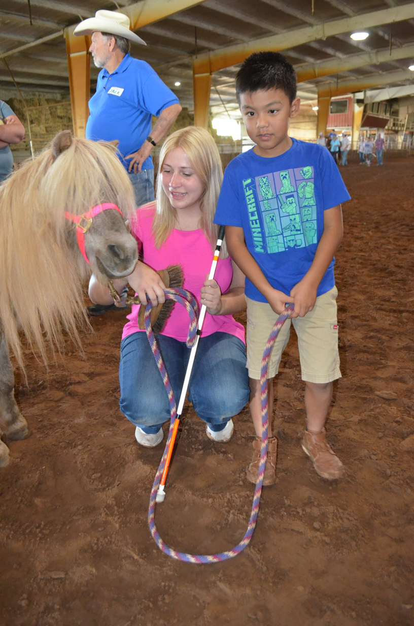A volunteer and a students have a pony by the lead.