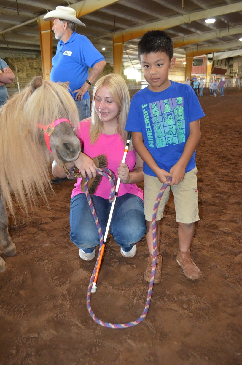 A volunteer and a students have a pony by the lead.