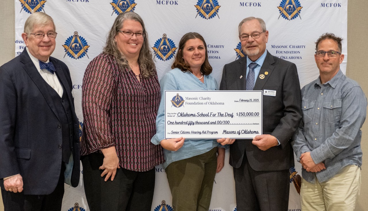 Five people pose for a photo holding 150,000 big check. 