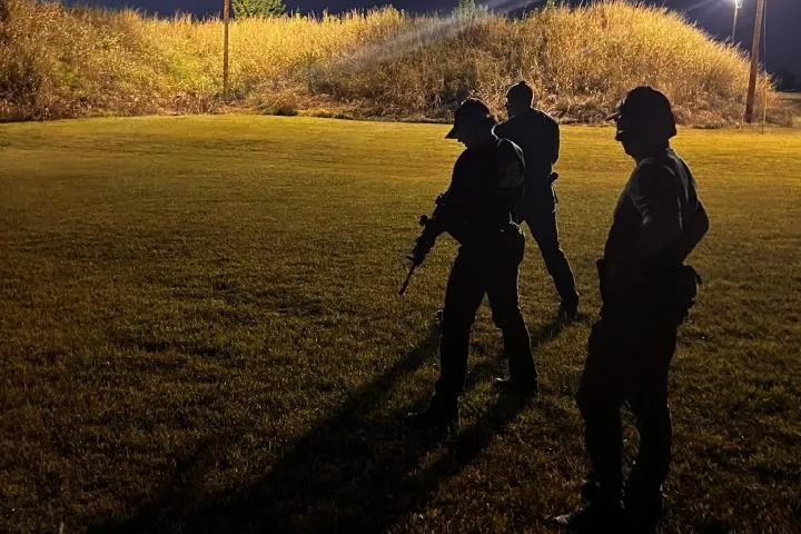 policemen in silhouette on a grassy field at night