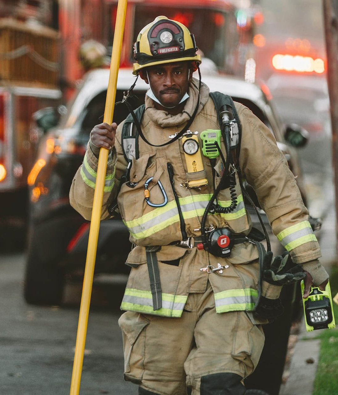 firefighter in gear standing with emergency services in background