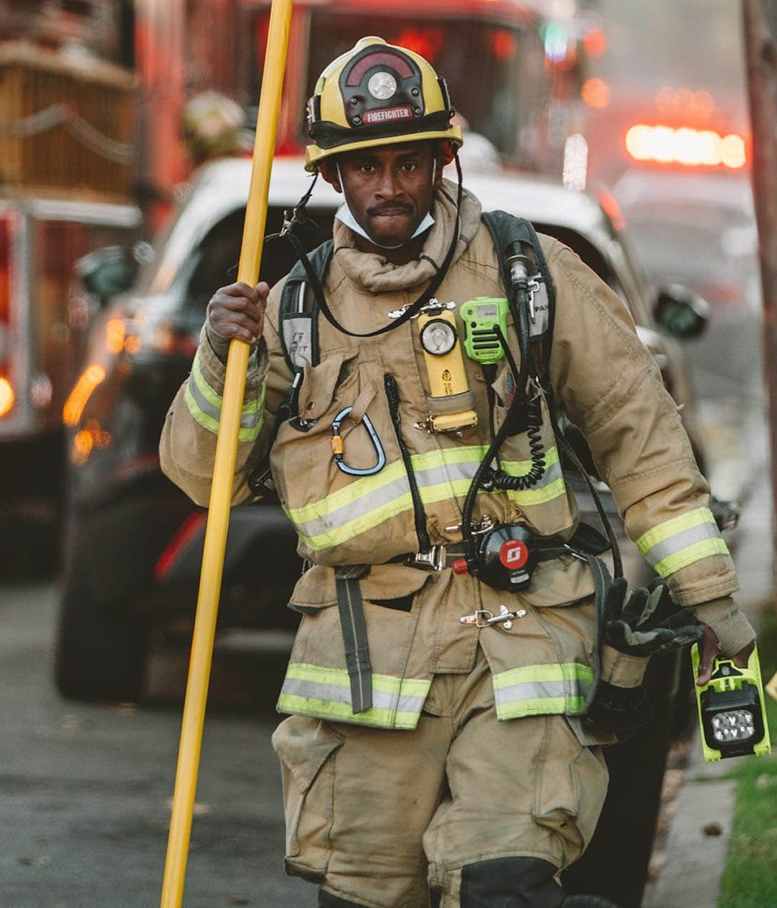 firefighter in gear standing with emergency services in background