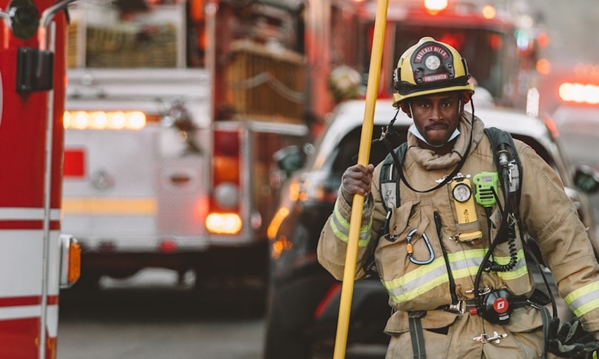 firefighter standing near red fire truck during daytime