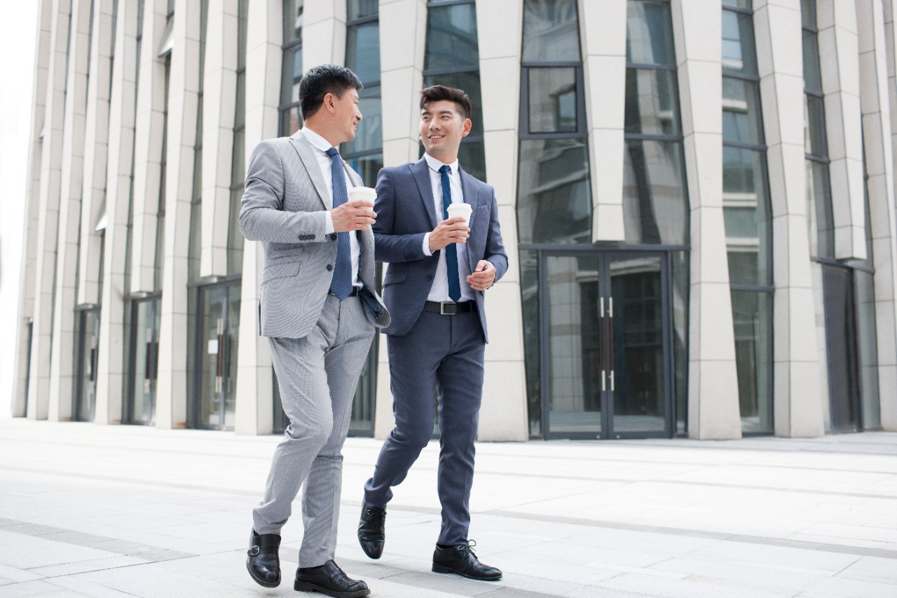 Confident Chinese businessmen talking and walking outdoors