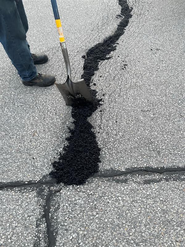 Close-up of large crack in Hodge building parking lot filled with fresh asphalt