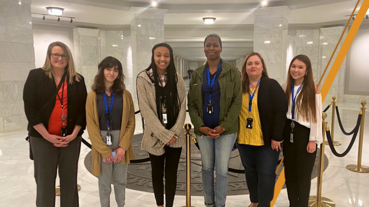 Three interns and three OMES Human Resources employees stand in front of the bronze state seal in the ground-floor rotunda of Oklahoma State Capitol Building.