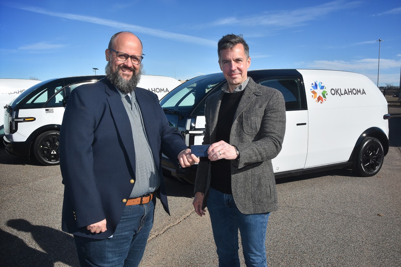 Canoo VP Chris Moore (right) hands off the Canoo vehicle key card to OMES Director of Enterprise Services Nathan Pumphrey (left).