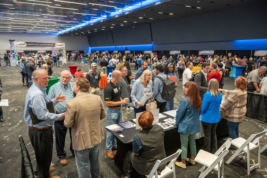 Wide angle of state staff engaging with suppliers across the ballroom