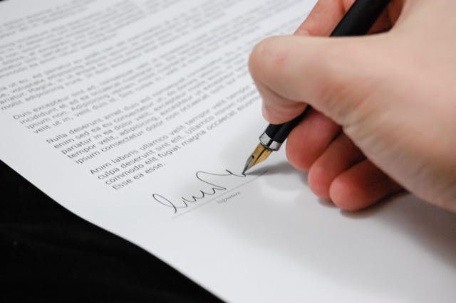 Decorative image of a hand signing a document