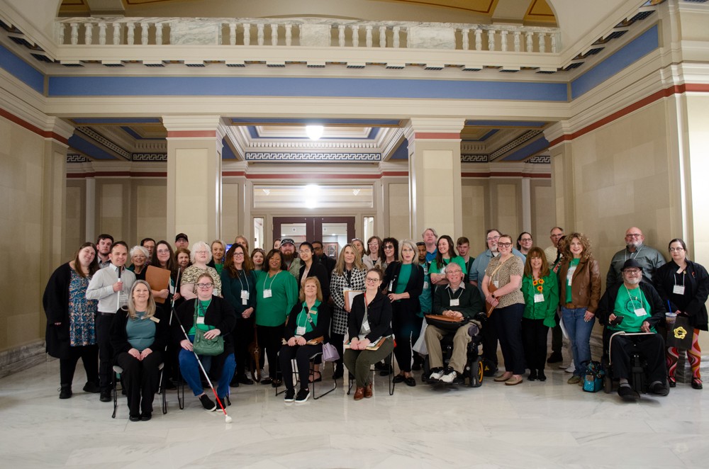 Large group of people pose for the camera at the state capitol. 