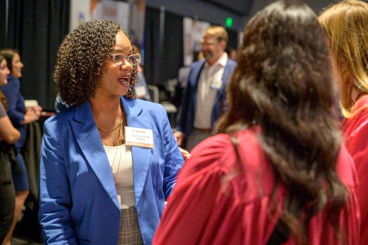 Ayana Wilkins talking to attendees at the Government Efficiency and Technology booth.