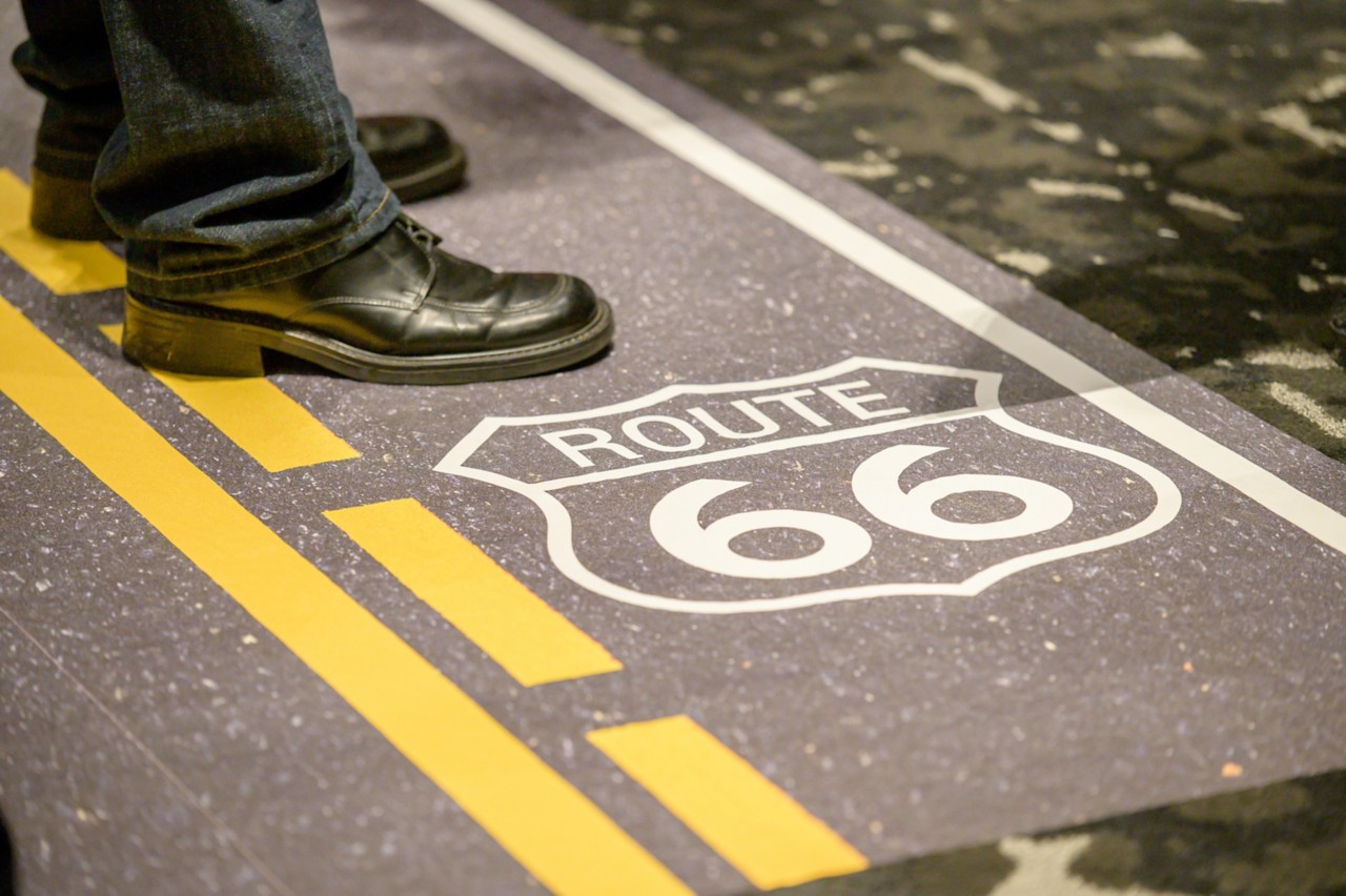 Person standing on a Route 66 road floor decal in front of the Transportation booth.