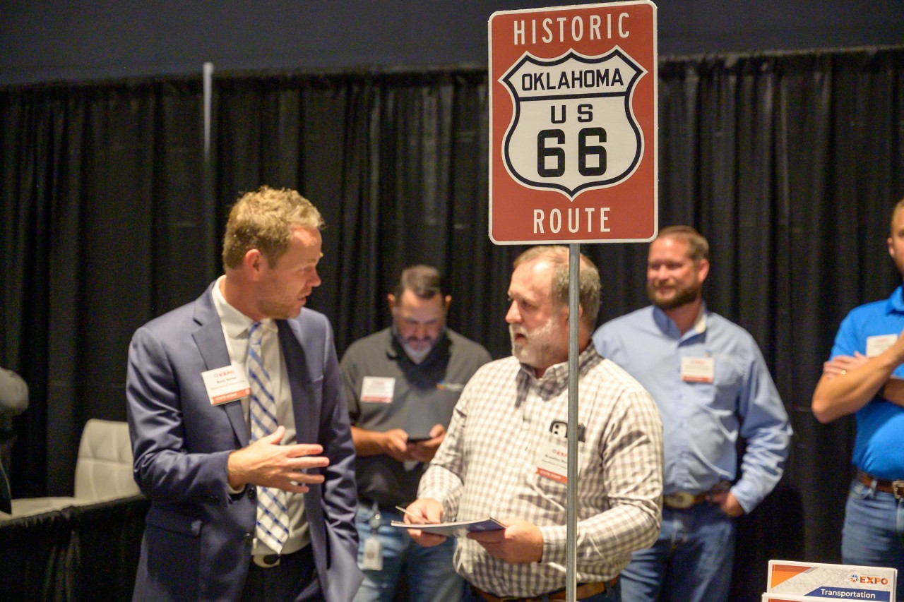 Transportation cabinet staff talking behind a Route 66 sign.