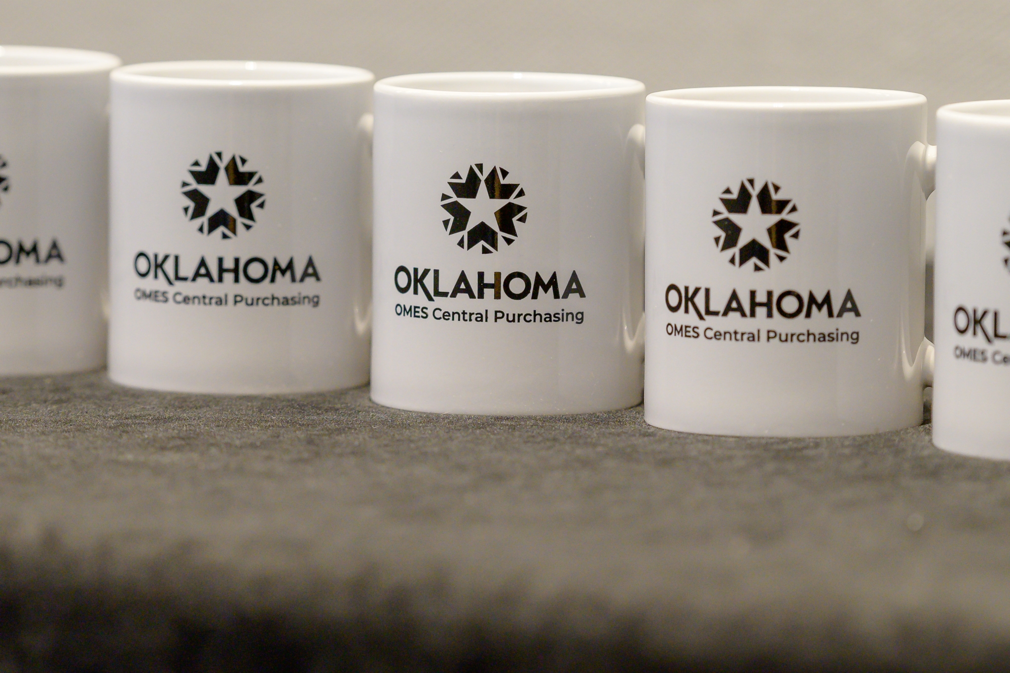 Oklahoma OMES Central Purchasing mugs at the Expo swag table.