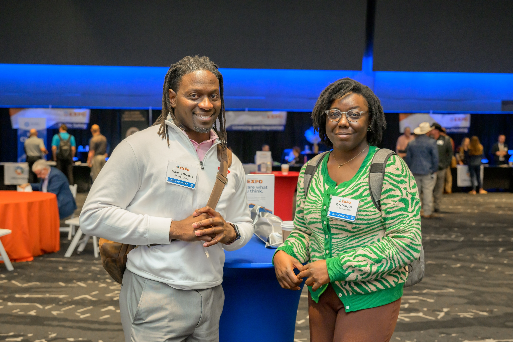 Two attendees smiling by a bistro table