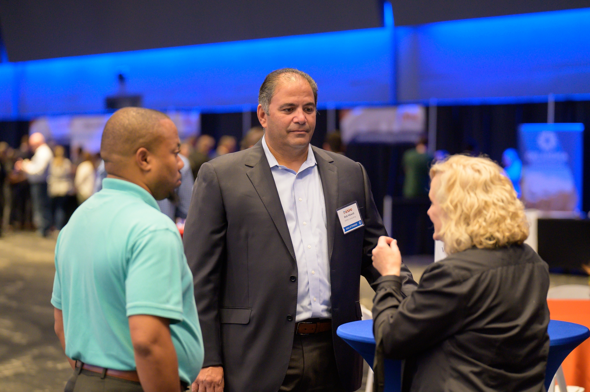 Three attendees chat near a bistro table