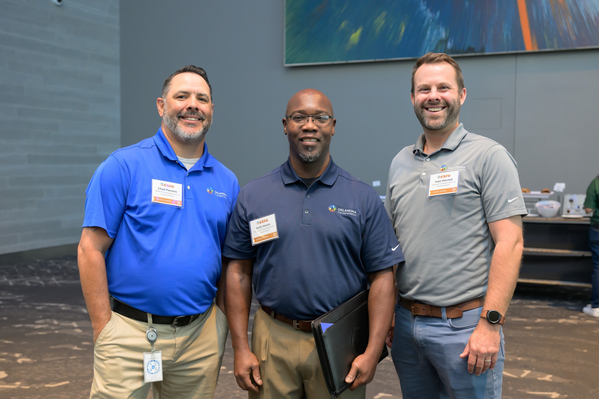 Three state staff members stand smiling
