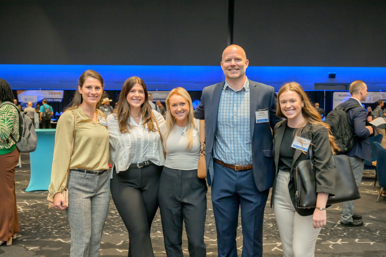 Five attendees stand in a group smiling