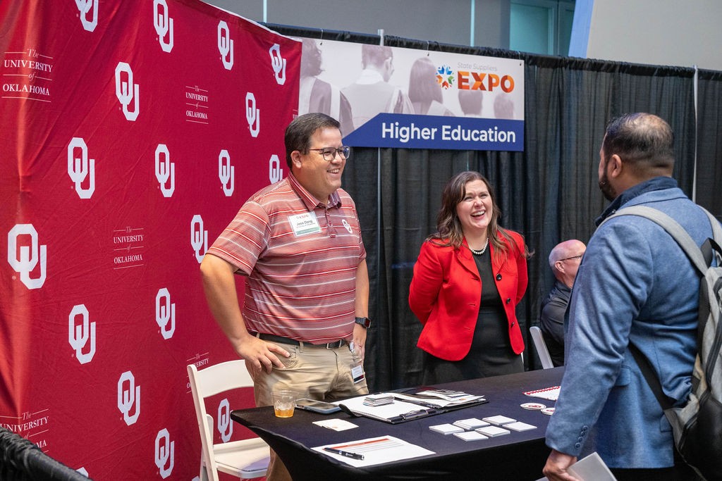 OU staff stand and laugh with supplier attendee