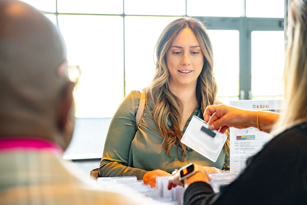 Woman receives an event name badge from check-in staff