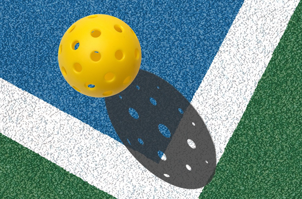 Pickleball Closeup of a yellow pickleball on a pickleball court