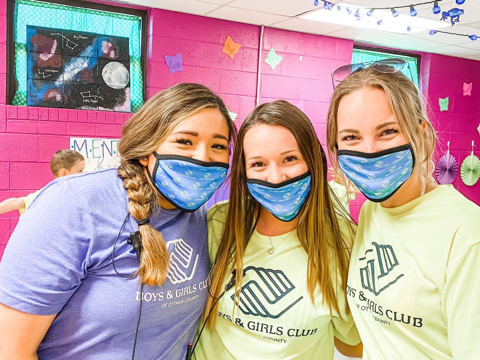 Three women smiling with face masks at a Boys & Girls Club event