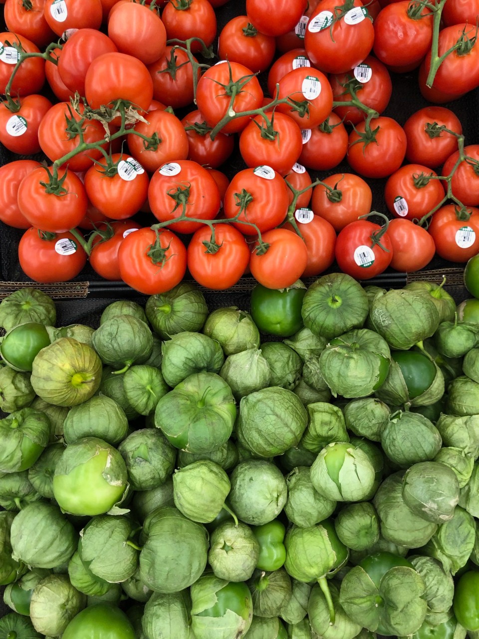 Grocery store display of tomatoes and tomatillos. 